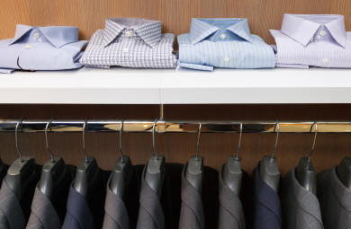 Row of men suit jackets on hangers and shelf with shirt in clothing store